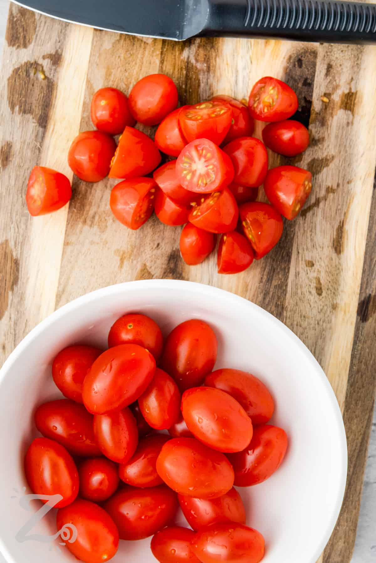 tomatoes being chopped on a cutting board