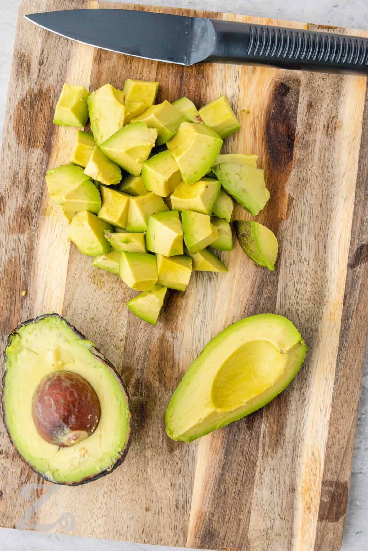 Avocado being chopped on a cutting board