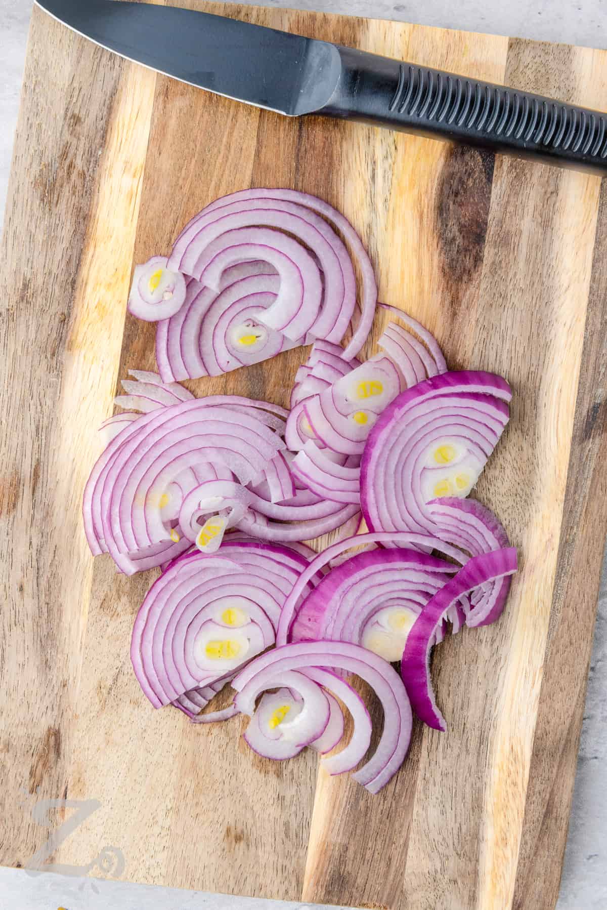 red onion being sliced on a cutting board