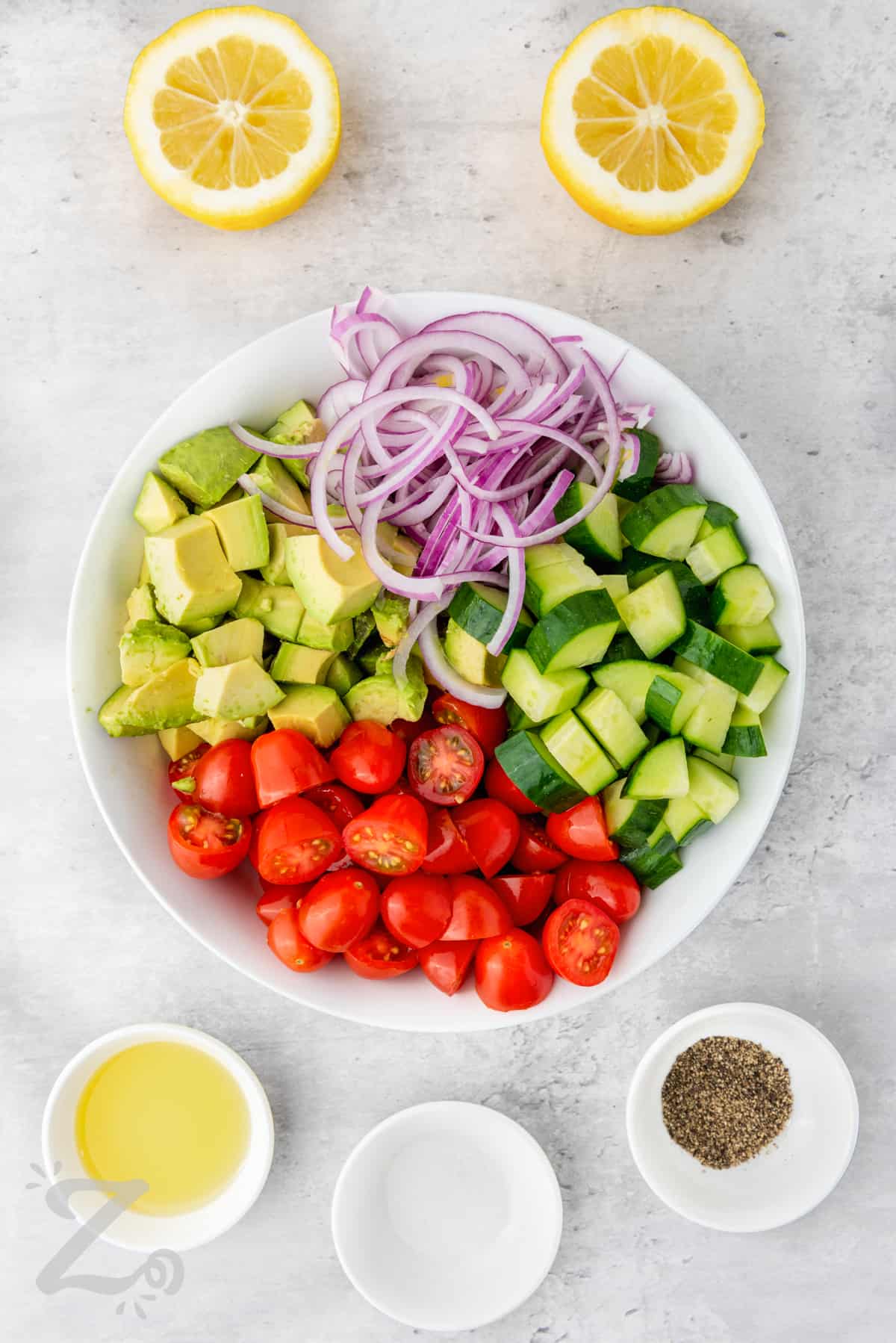 ingredients to make avocado salad in a bowl with the dressing ingredients on the side