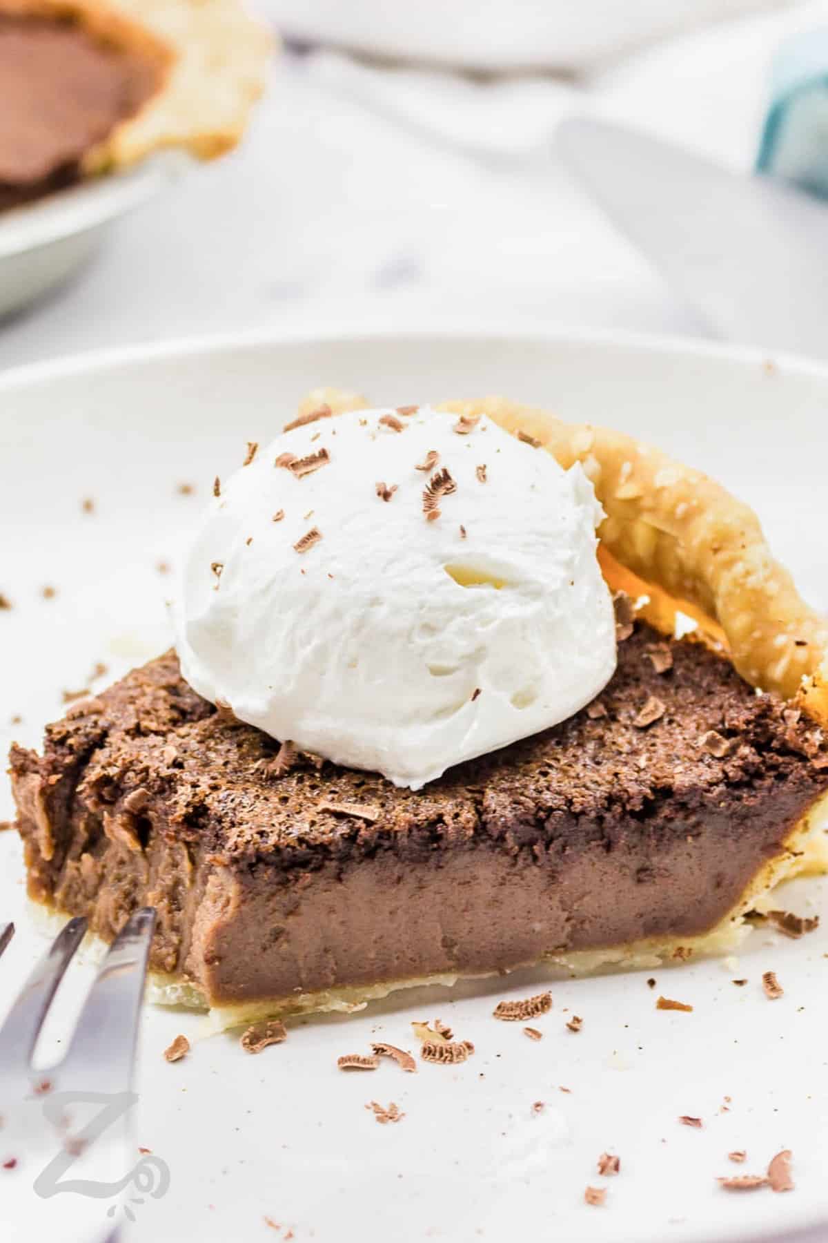 Chocolate chess pie topped with whipped cream with a bite missing