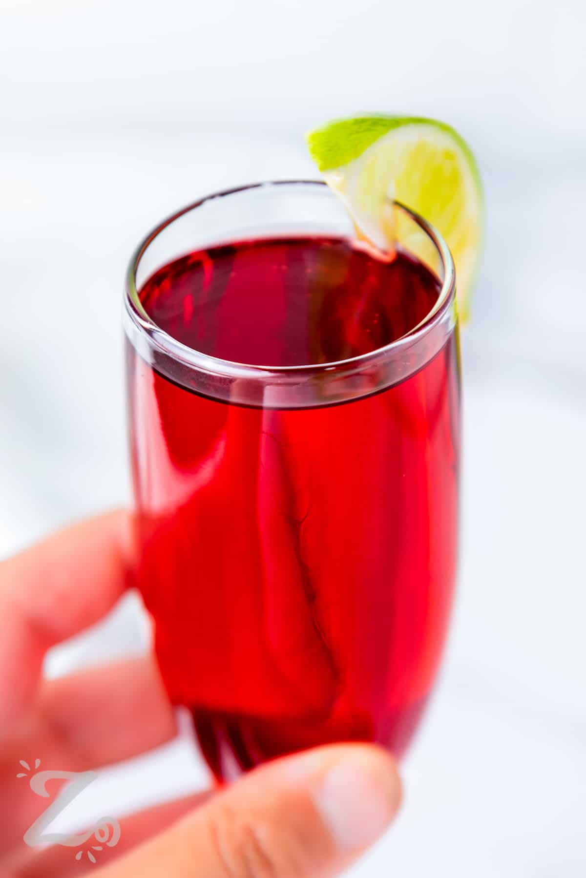 close up of holding a Cranberry Mimosas with a lime wedge