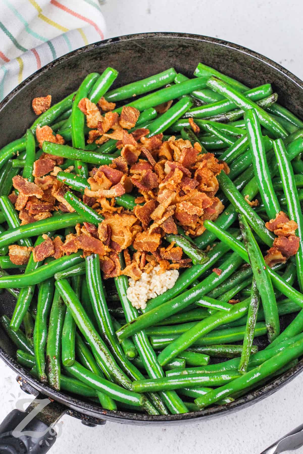 adding bacon and garlic to beans to make Green Beans with Bacon