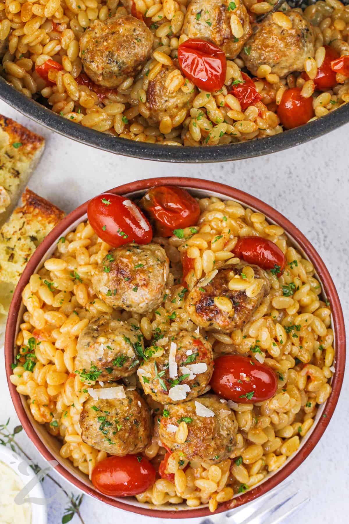 bowl of One Pot Tomato Orzo With Meatballs, garnished with parmesan