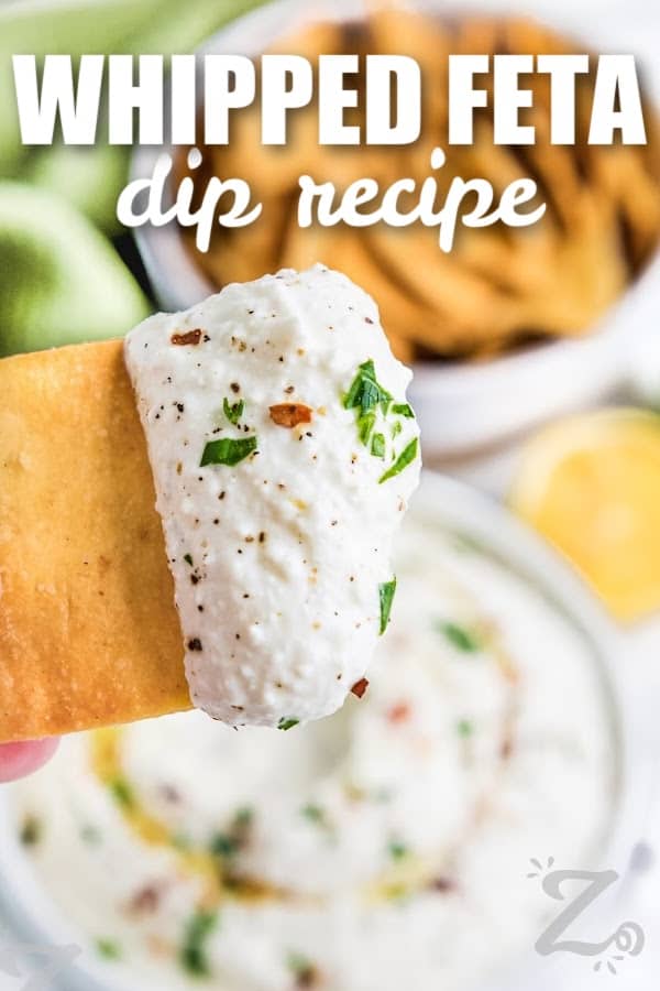 a cracker dipped in whipped feta dip with text
