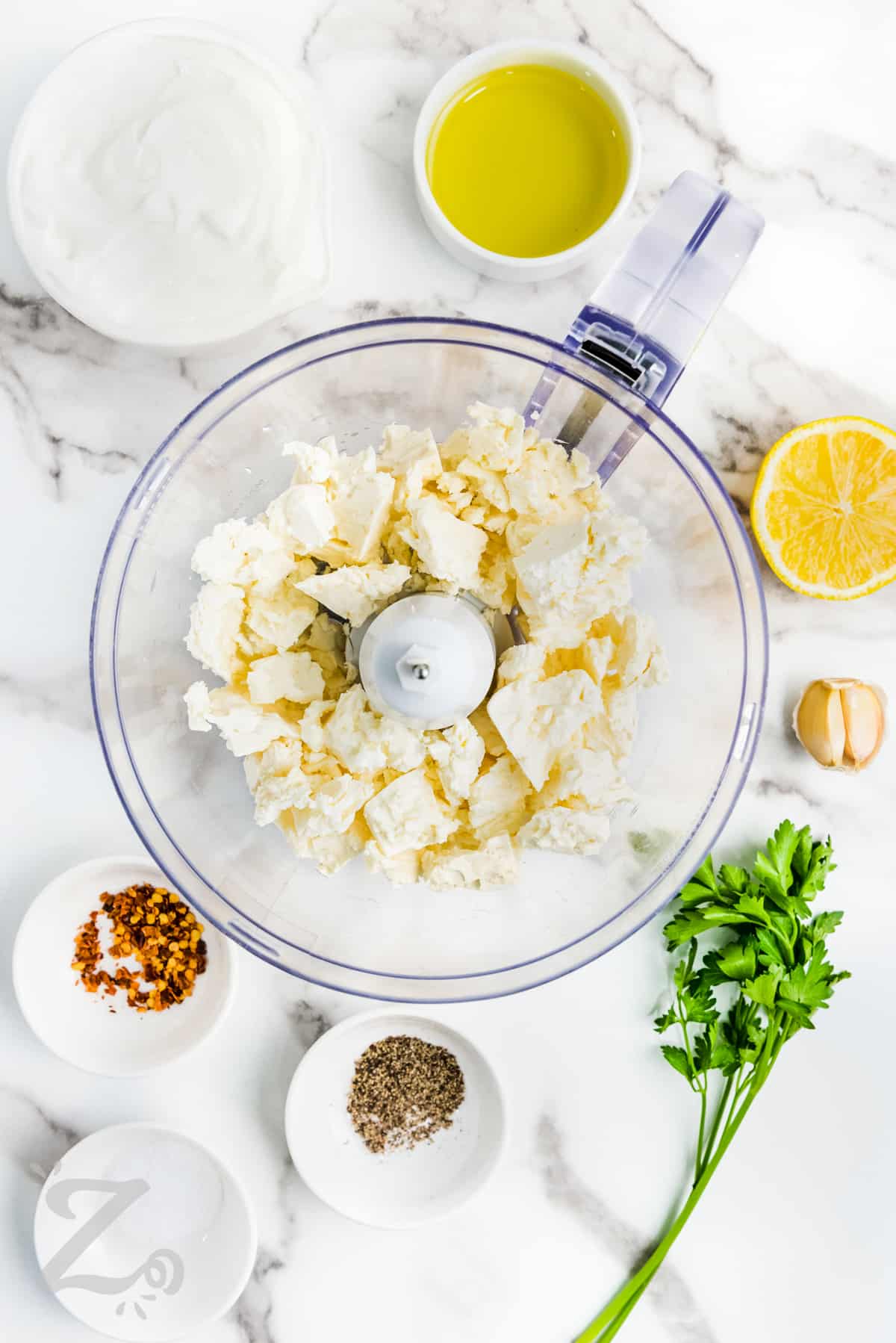 ingredients to make whipped feta dip being added to a food processor