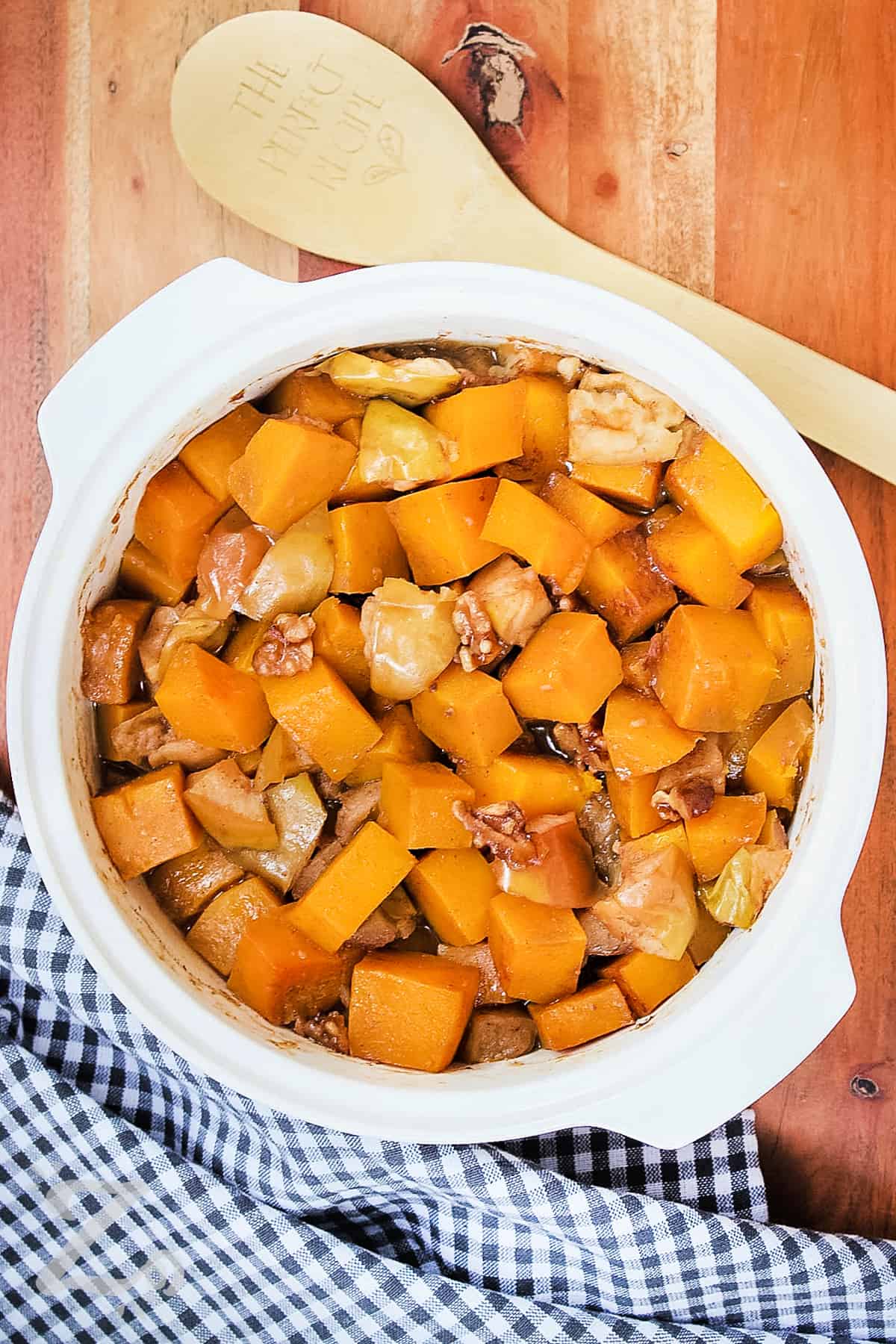 butternut squash casserole in a dish with a wooden spoon on the side