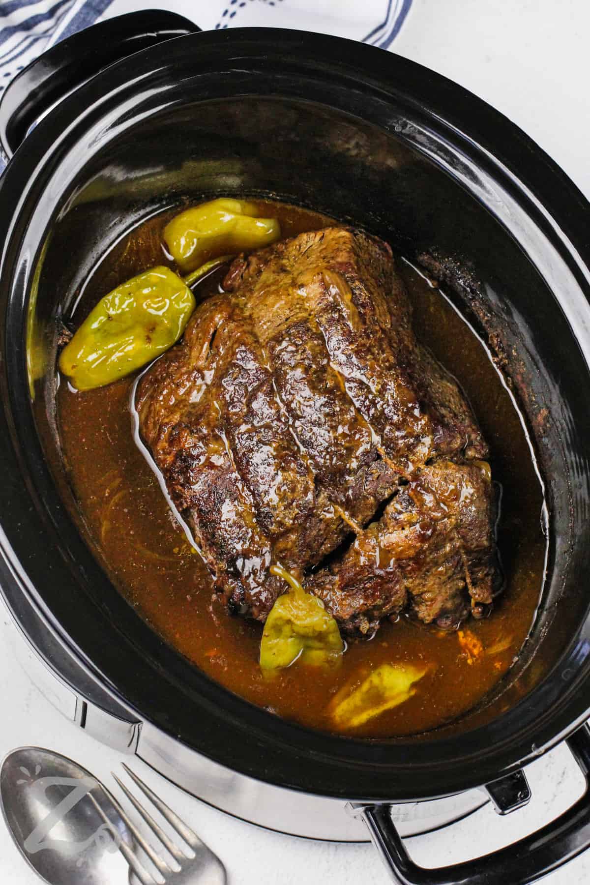 pot roast with peppers and juices in a slow cooker for slow cooker Mississippi pot roast