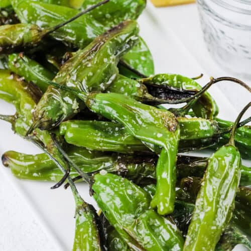 blistered shishito peppers on a white plate