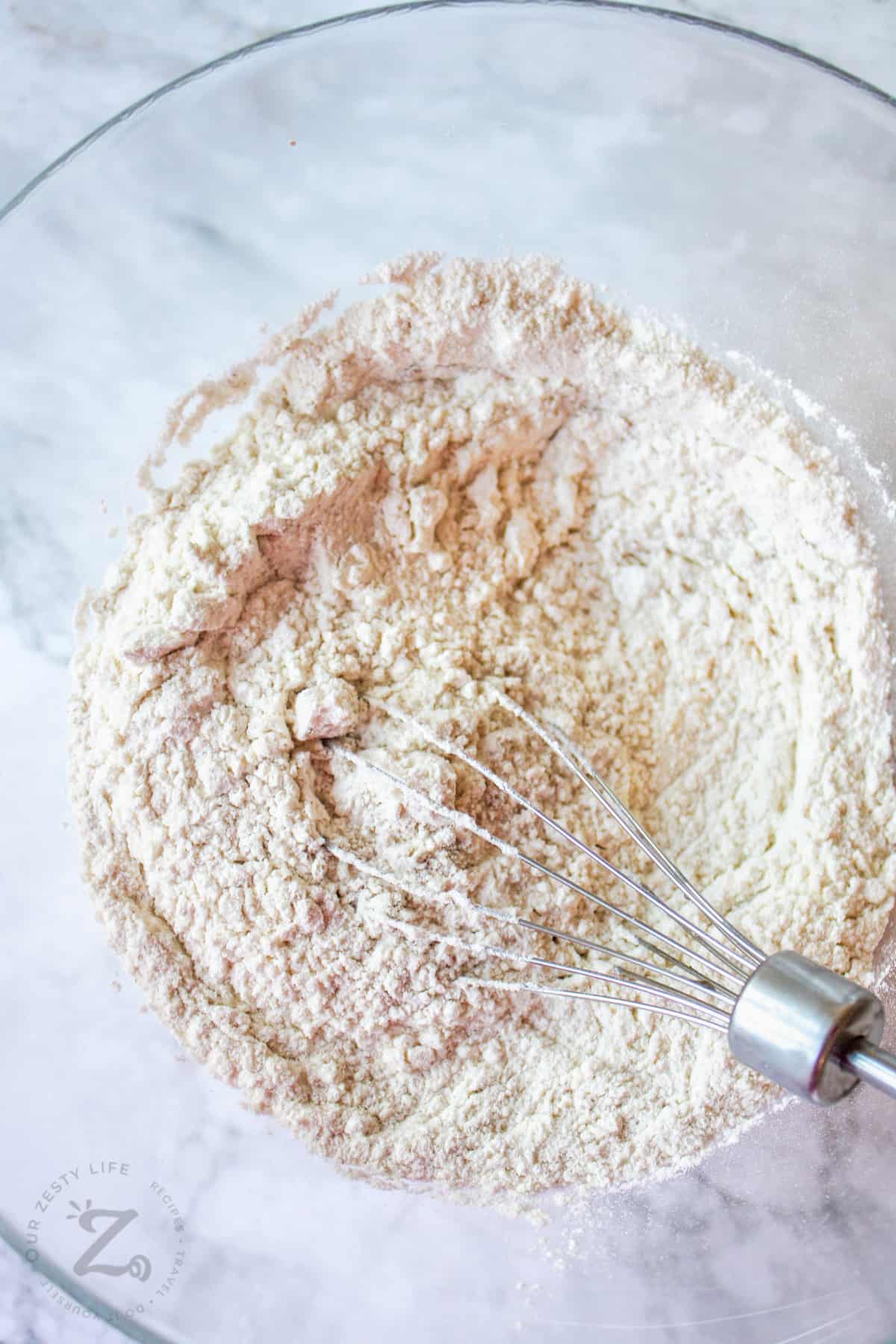 flour mixture with a whisk in a bowl for garlic herb bread