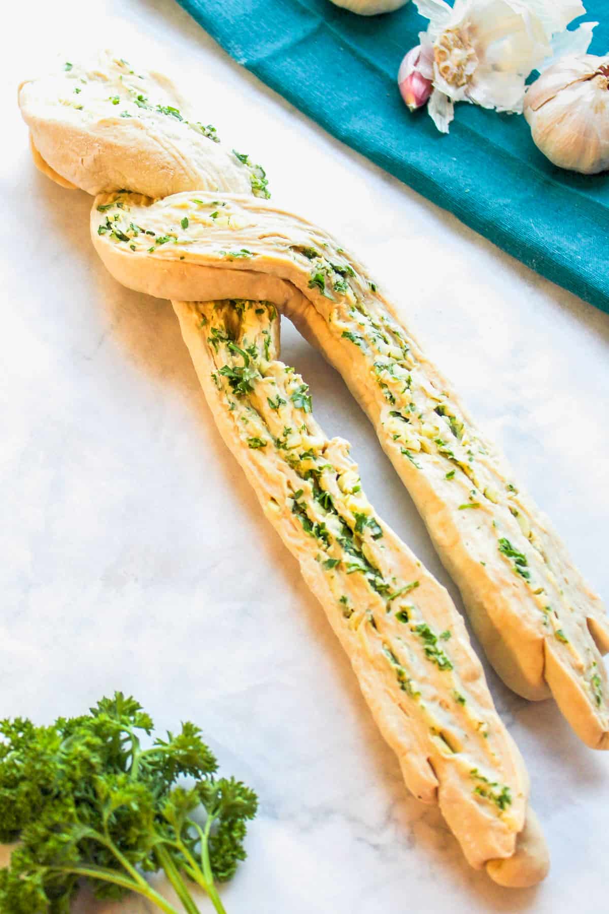 twisting raw dough for garlic herb bread