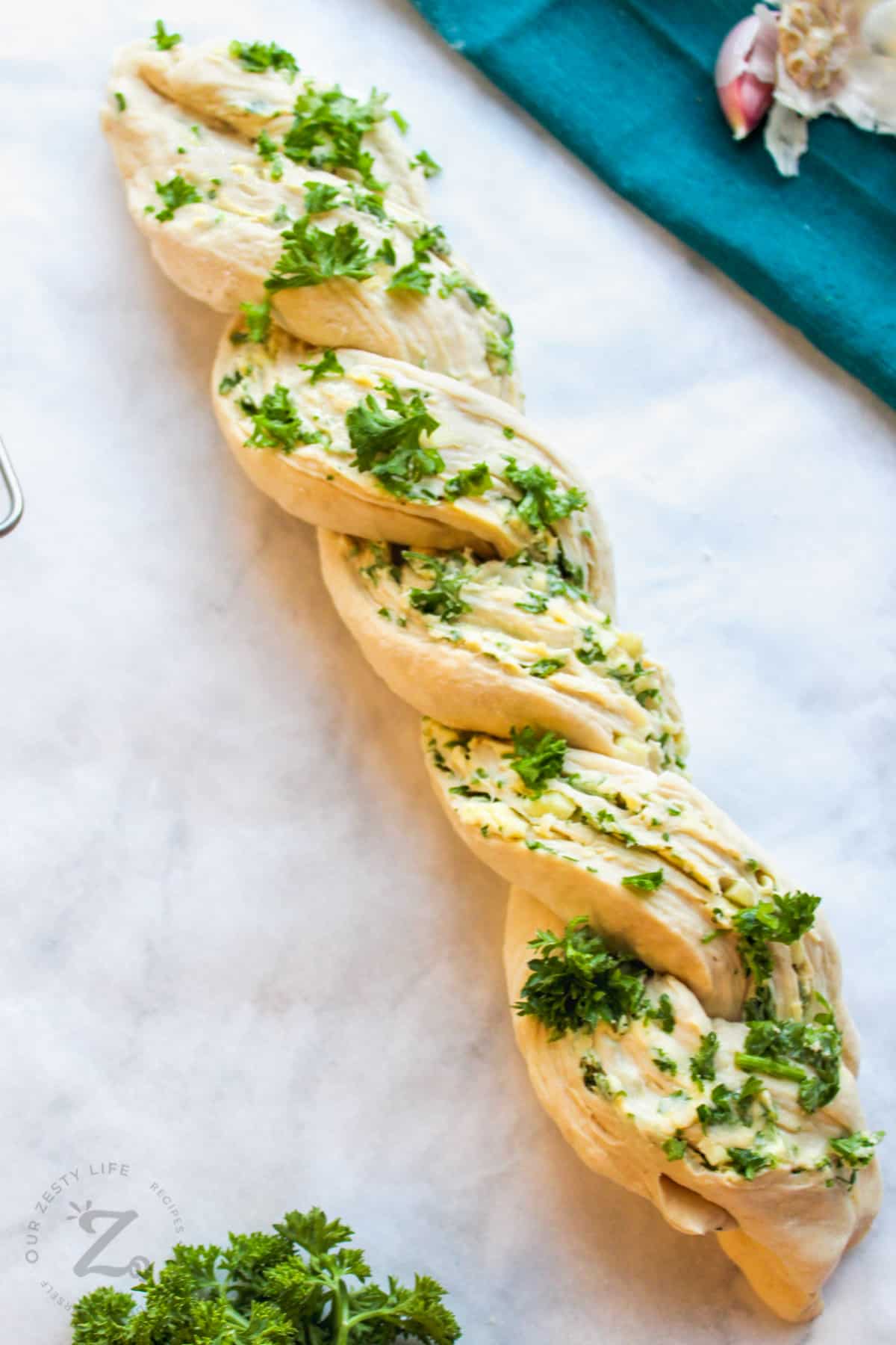 unbaked and twisted garlic herb bread on a marble board