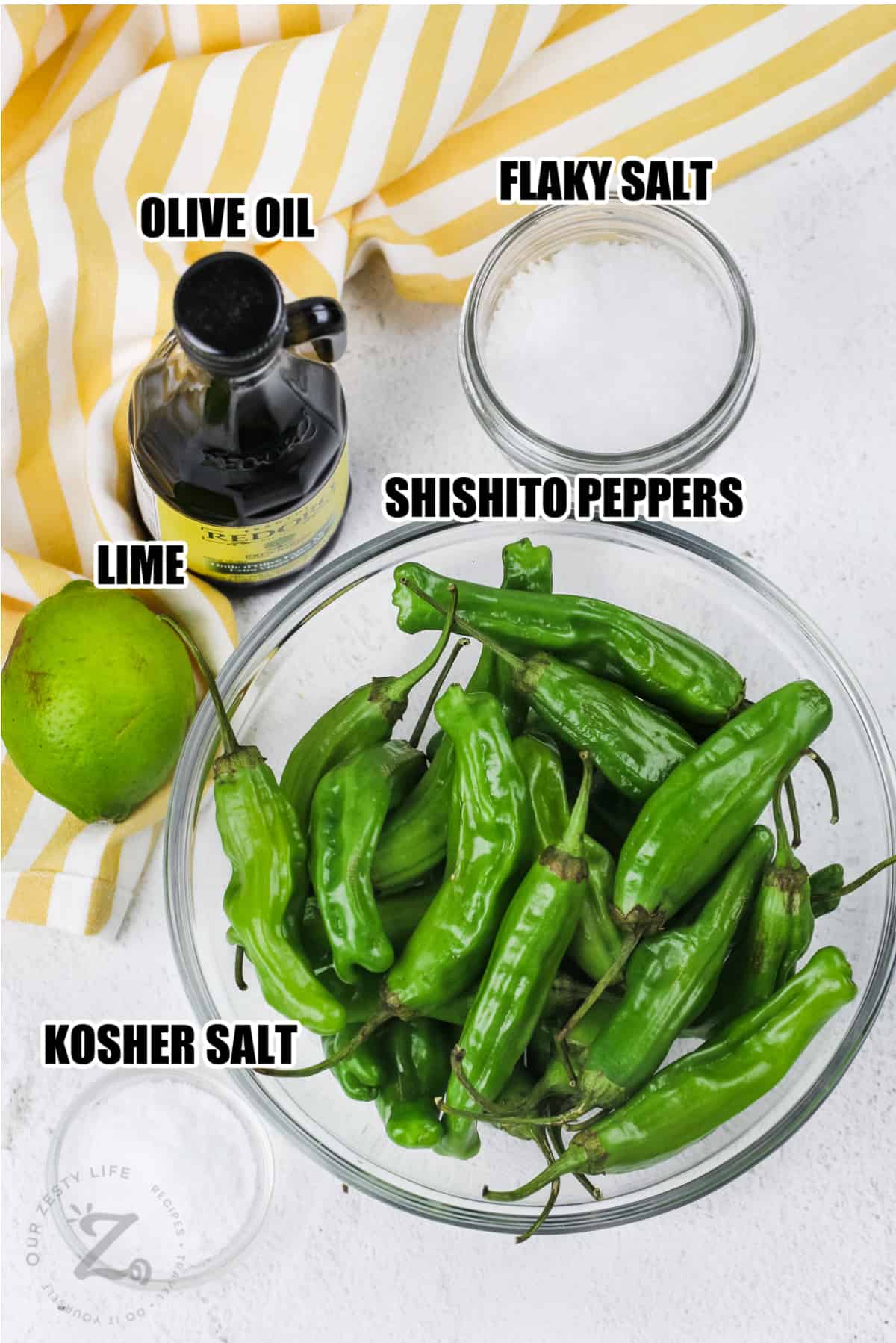 ingredients for blistered shishito peppers including shishito peppers, flaky salt, olive oil, lime, and kosher salt