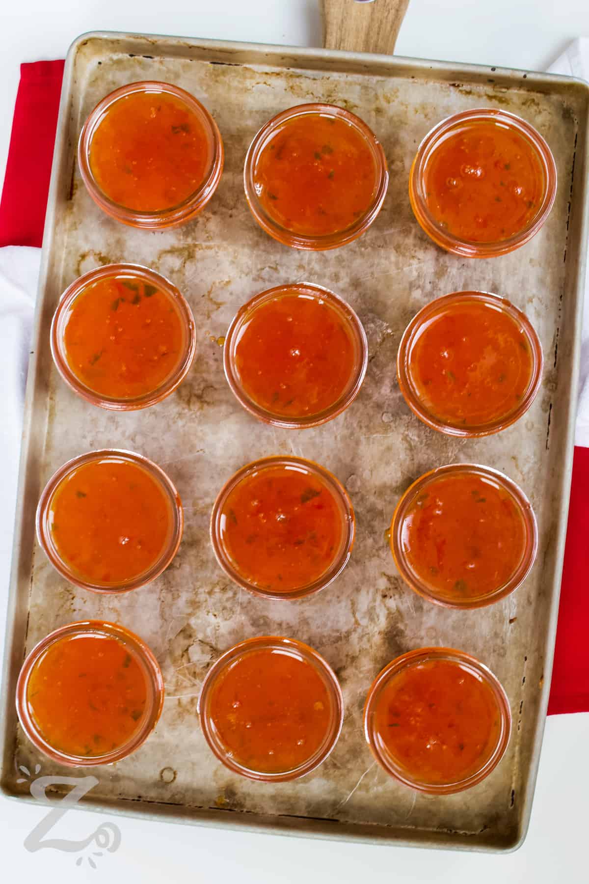 red pepper jelly in jars on a baking sheet