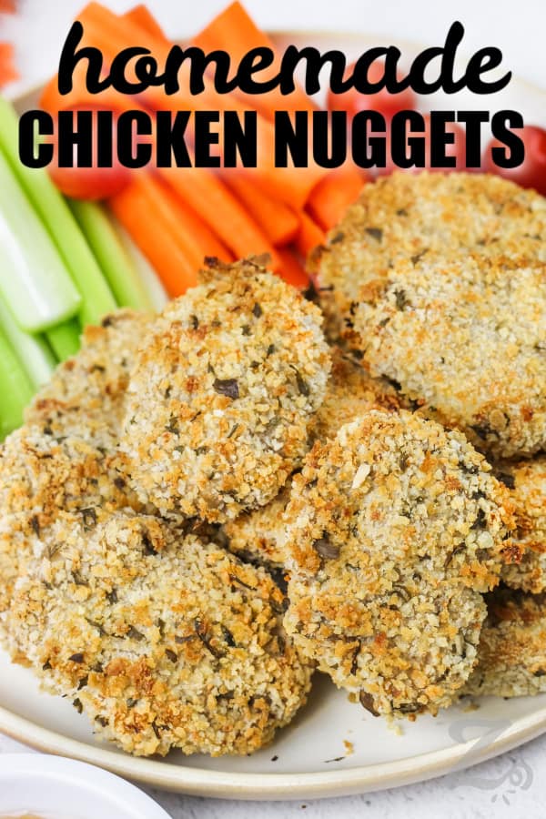 Chicken Nuggets on a plate with veggies in the background and a title
