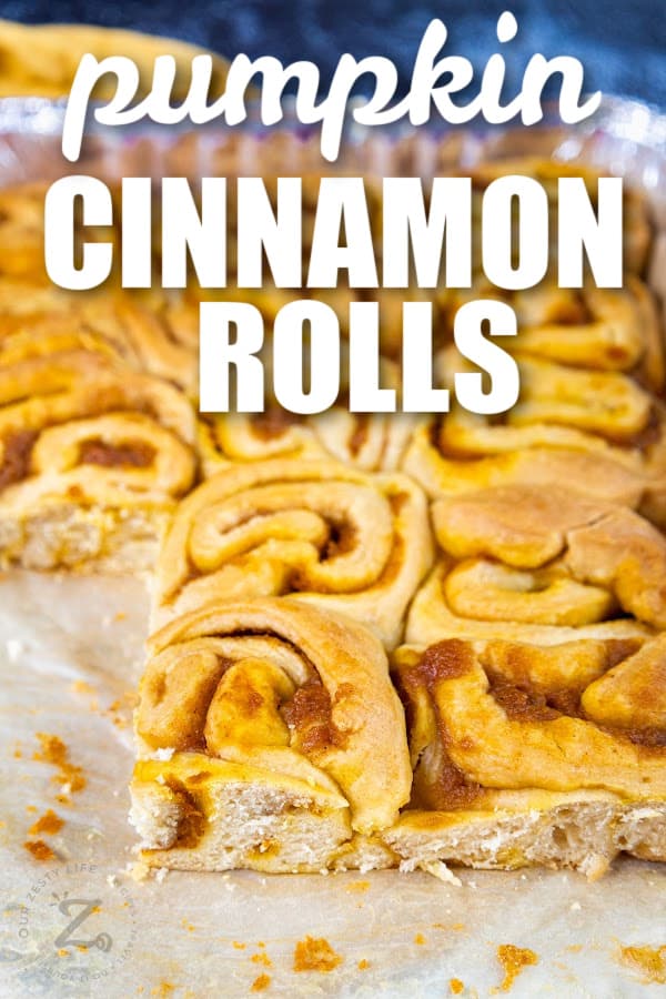 pumpkin cinnamon rolls in a pan with text