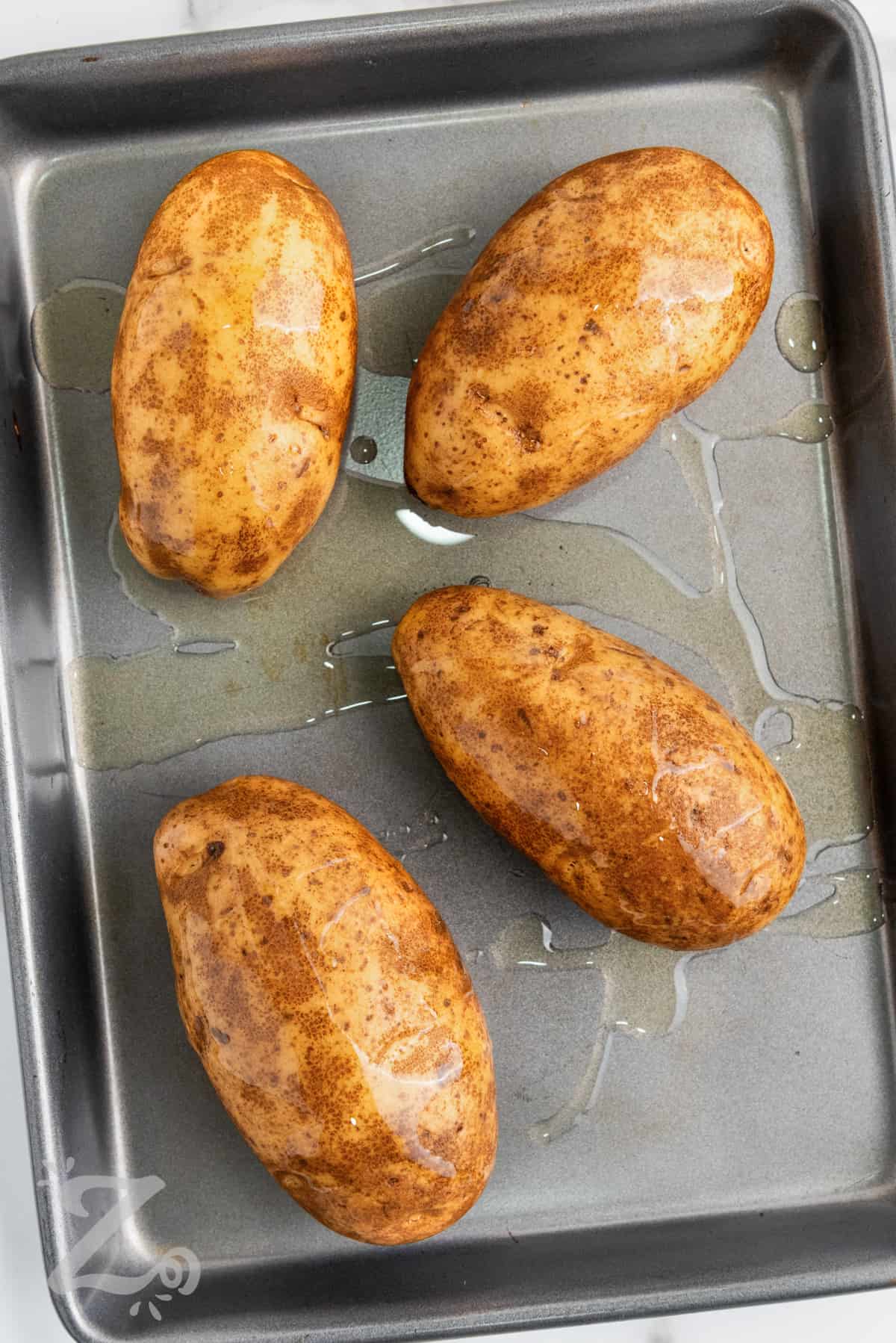 adding oil to potato skins to make Twice Baked Potatoes