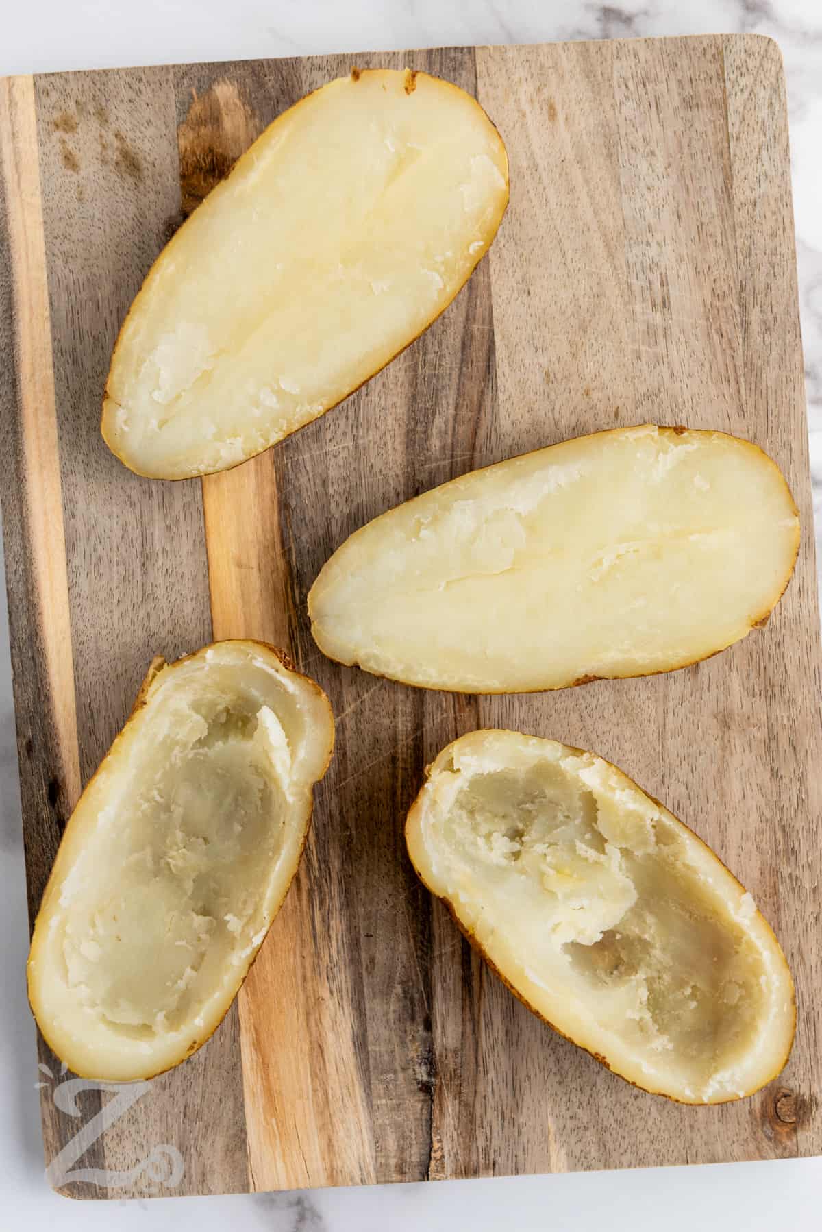 scooping out potatoes to make Twice Baked Potatoes