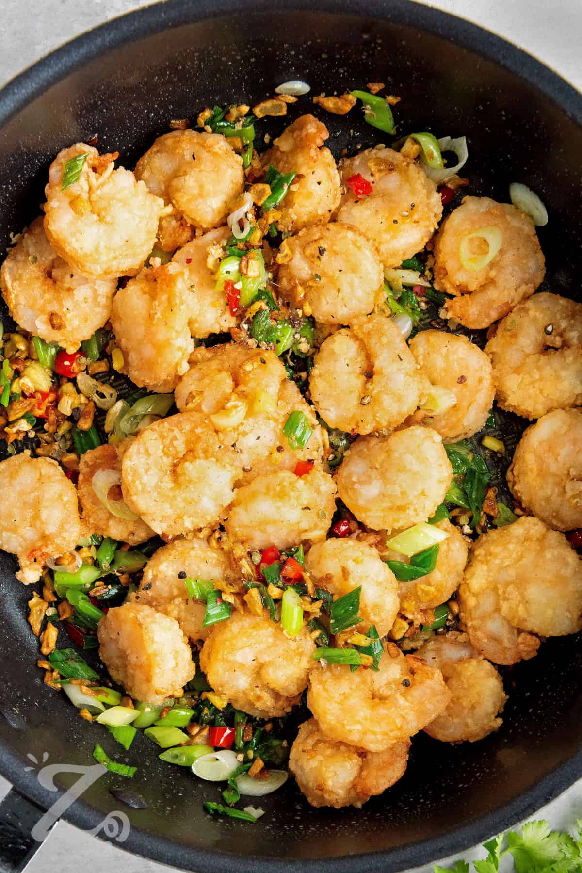 Deep fried shrimp tossed in a frying pan with seasonings