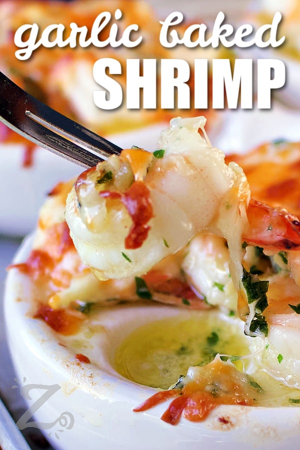 a cheesy garlic baked shrimp being pulled from an escargot dish with a shrimp fork, with writing