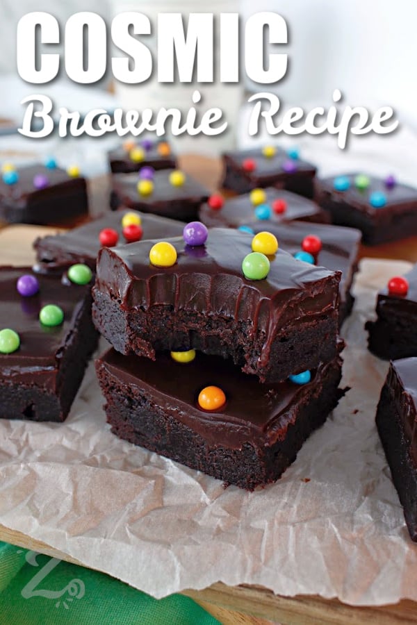 cosmic brownie recipe on a parchment lined paper, one stacked on another with a bite taken out, with a title