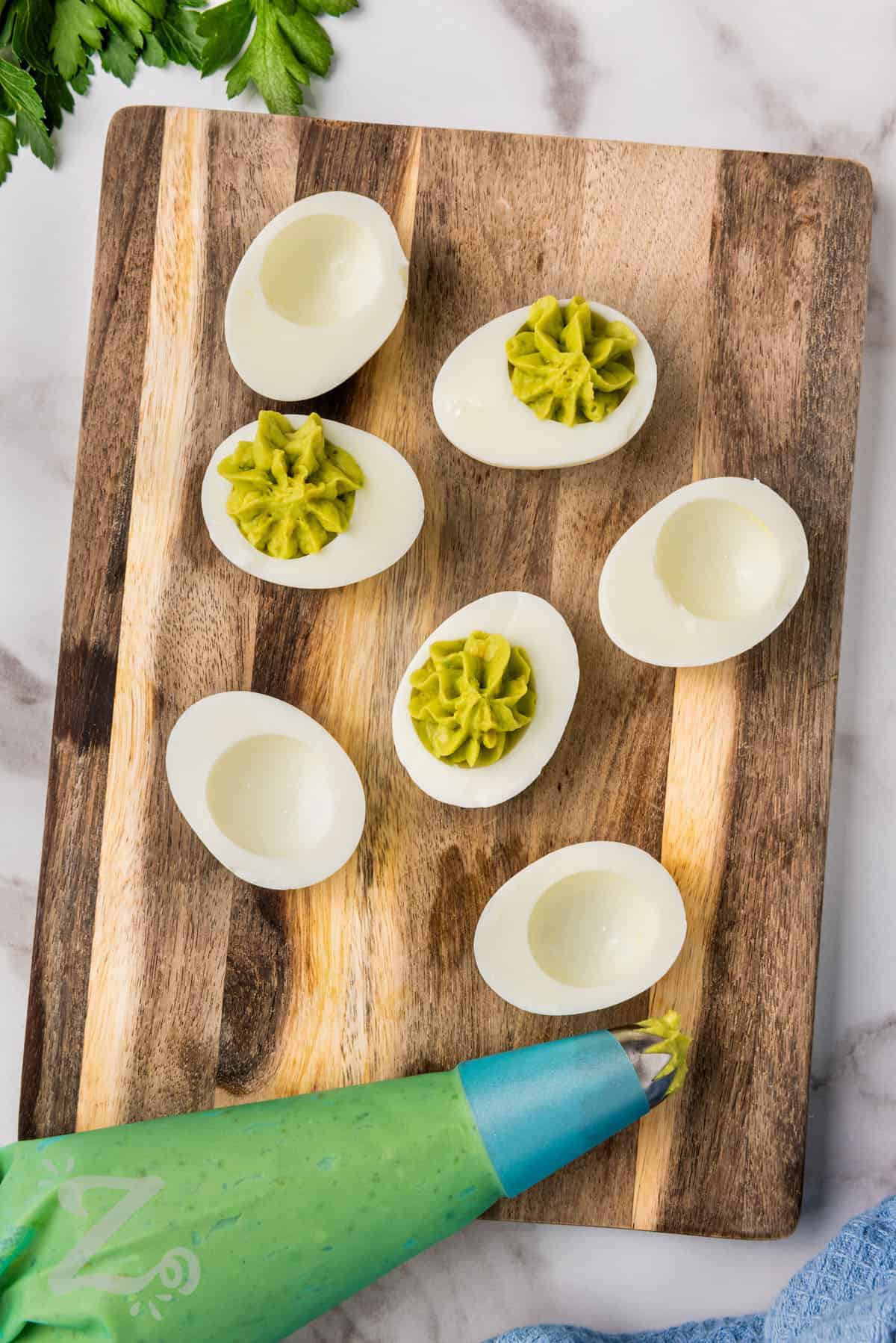 avocado deviled eggs filling being piped into cooked egg whites