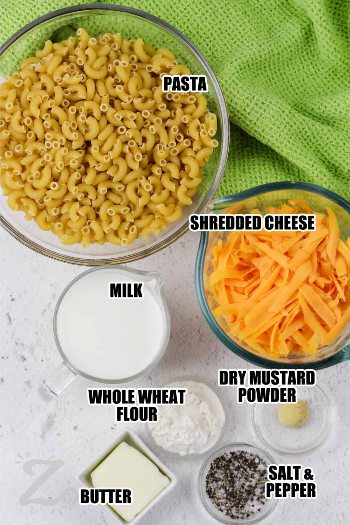 ingredients to make baked macaroni and cheese labeled: pasta, shredded cheese, milk, dry mustard powder, whole wheat flou, butter, salt and pepper