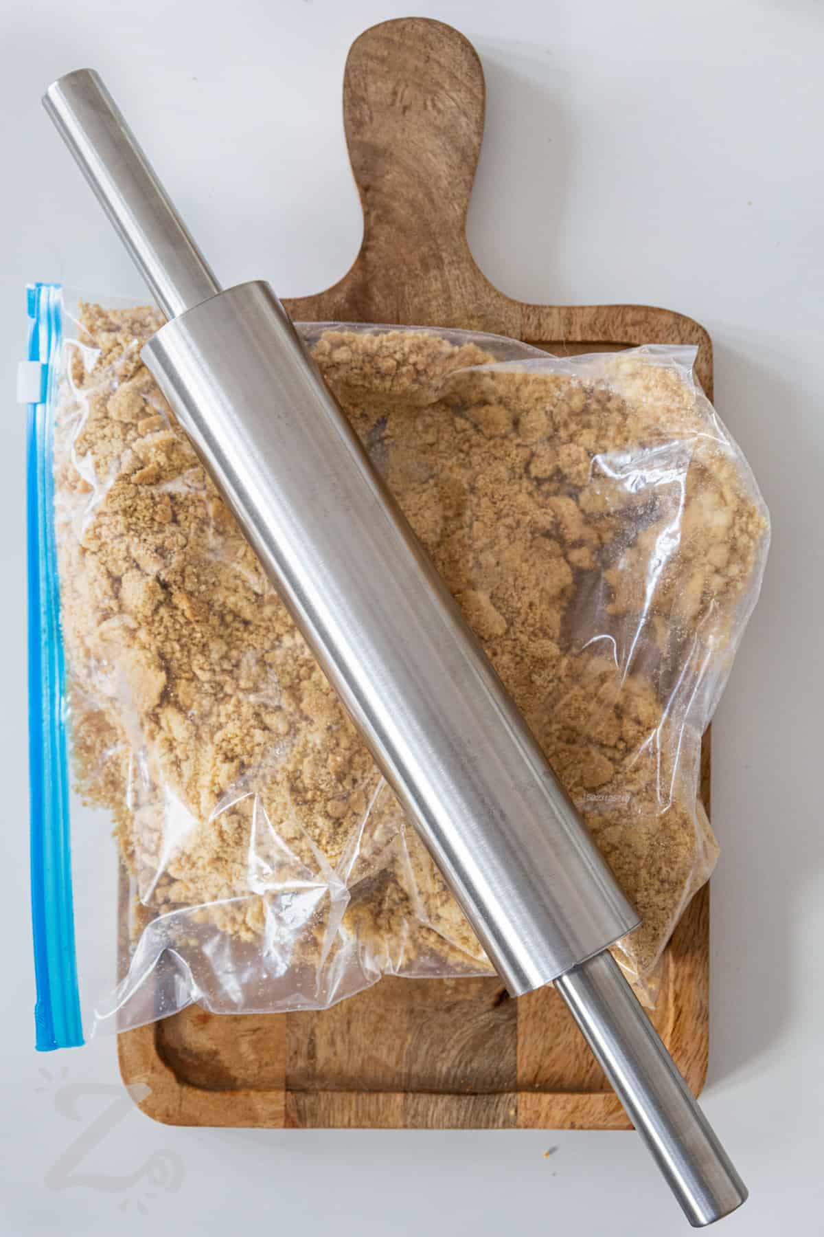 crisp cookies being crushed in a zippered bag with a rolling pin