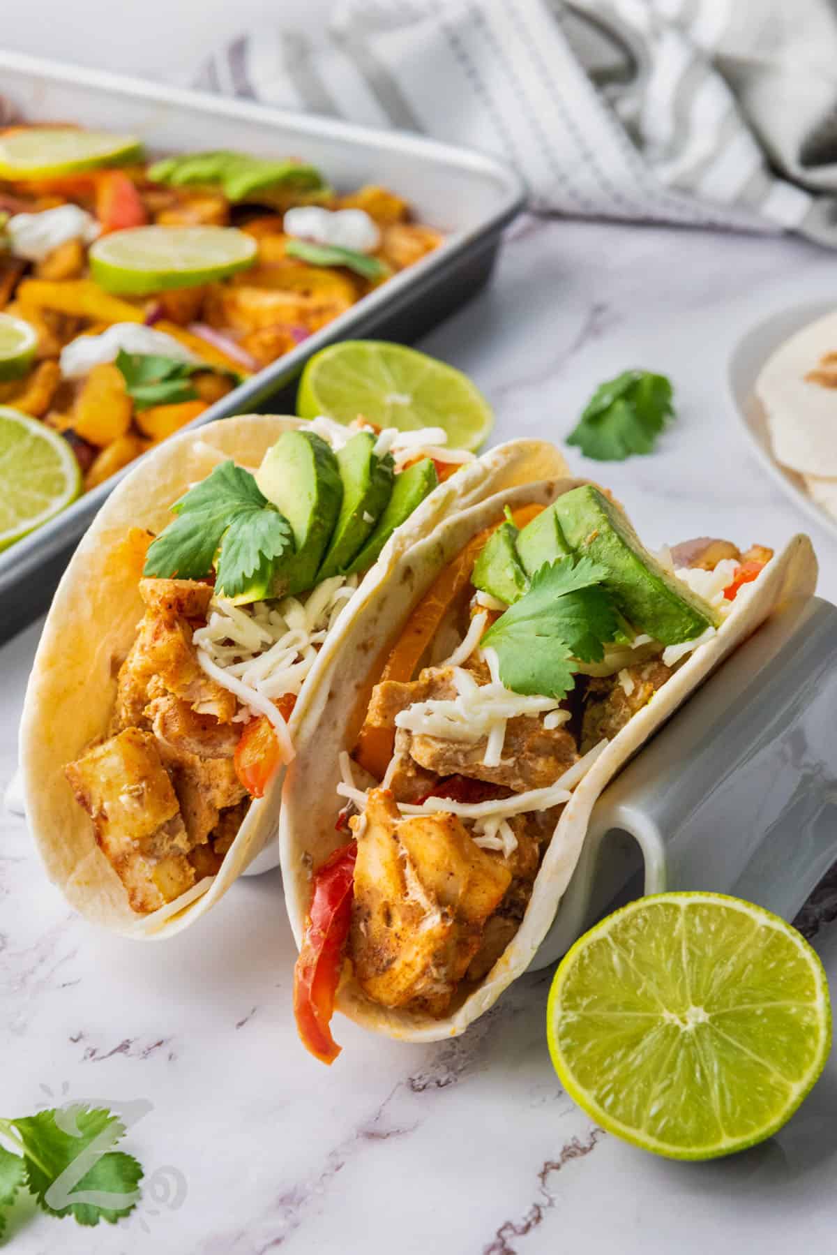 two chicken fajitas topped with avocados and cilantro