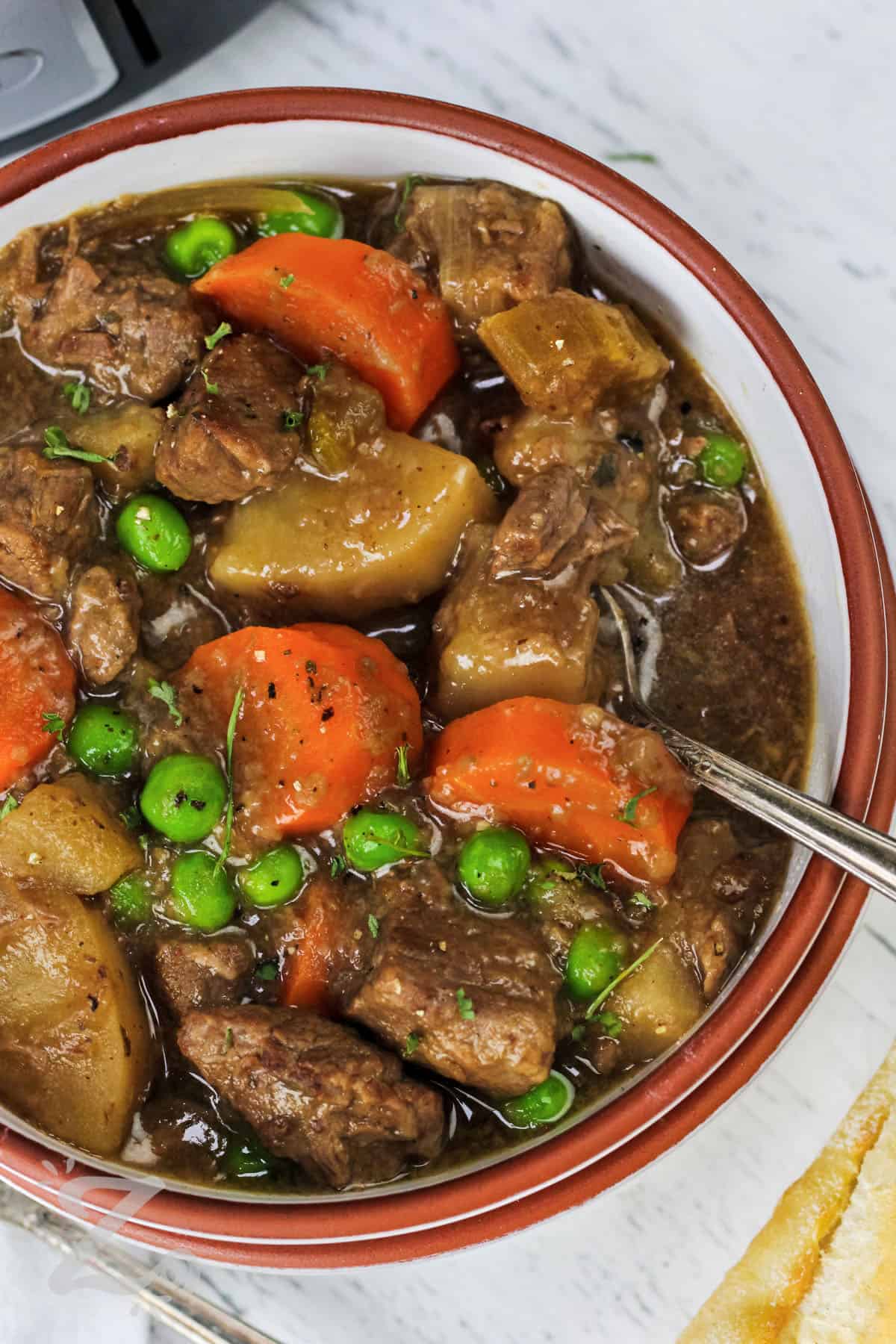 A bowl of slow cooker beef stew with a spoon in it