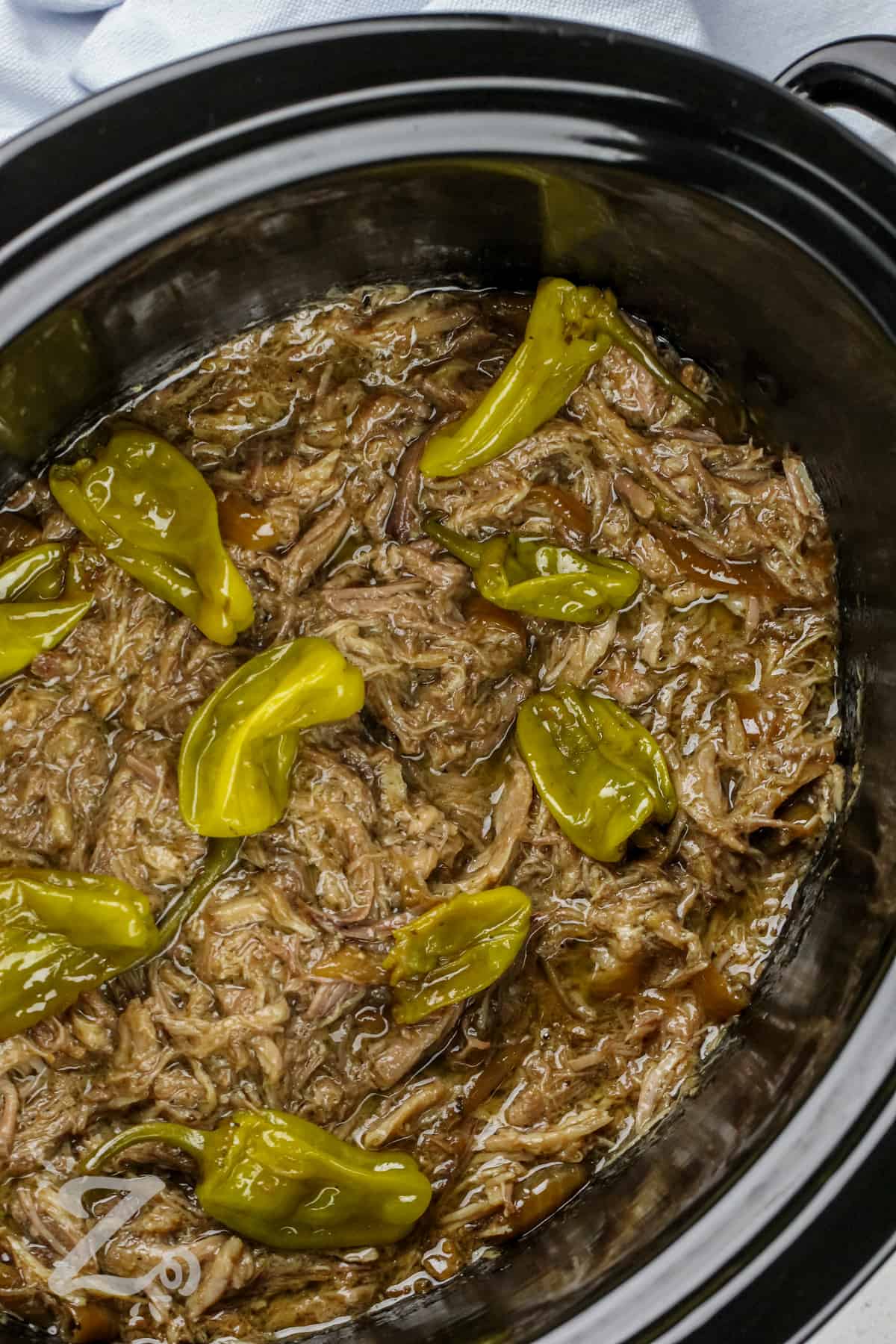 Shredded Mississippi Pork Roast in a slow cooker with pepperoncinis