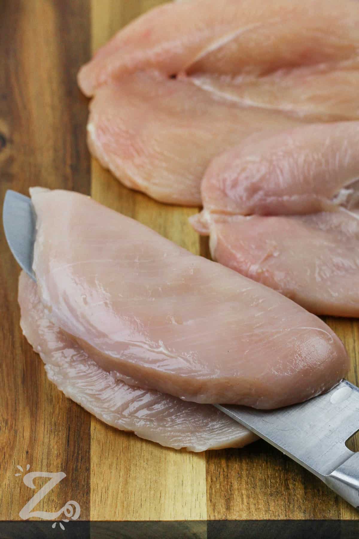 chicken breasts being sliced in half