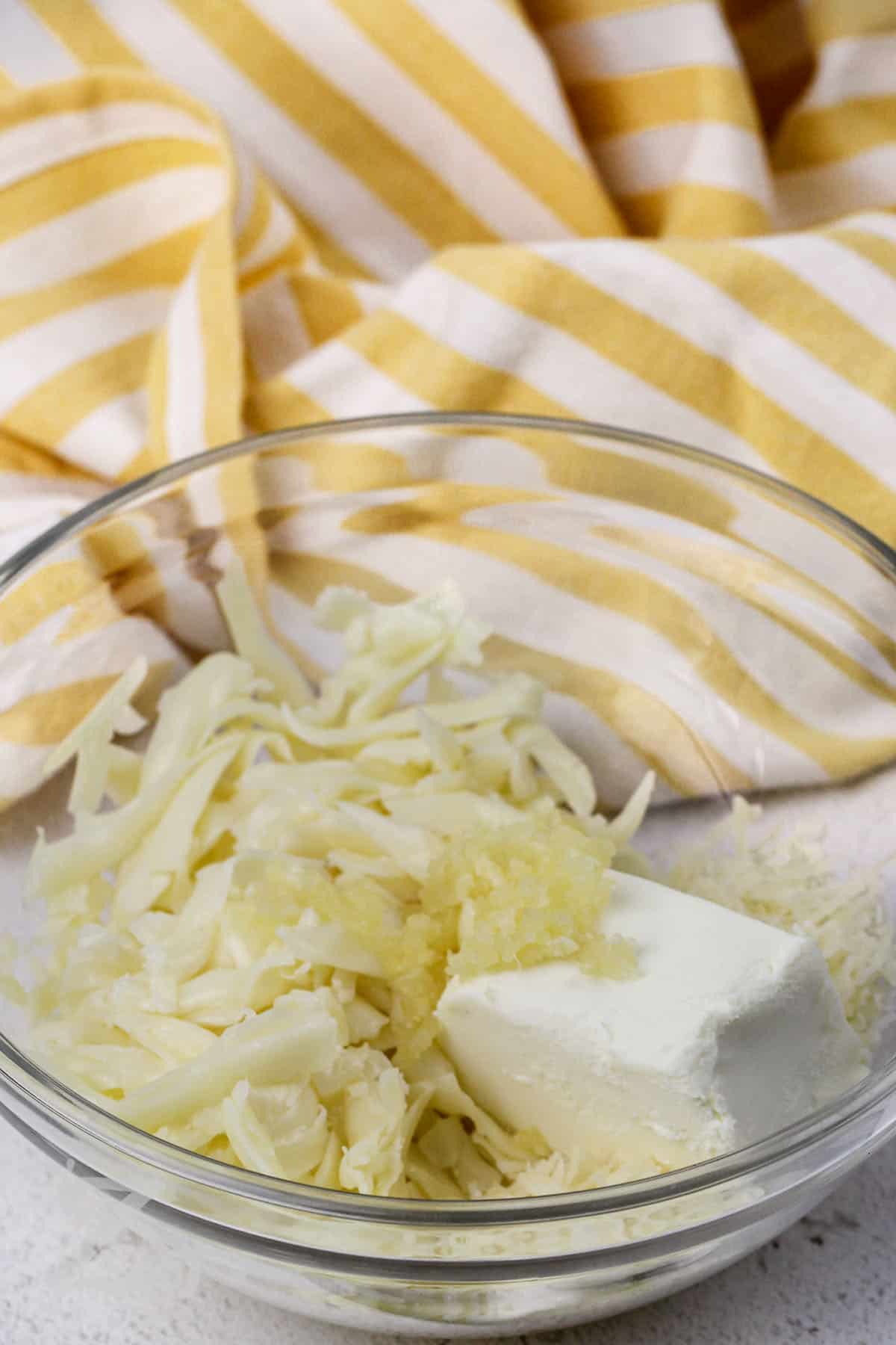 cream cheese, mozzarella, and parmesan being mixed in a bowl