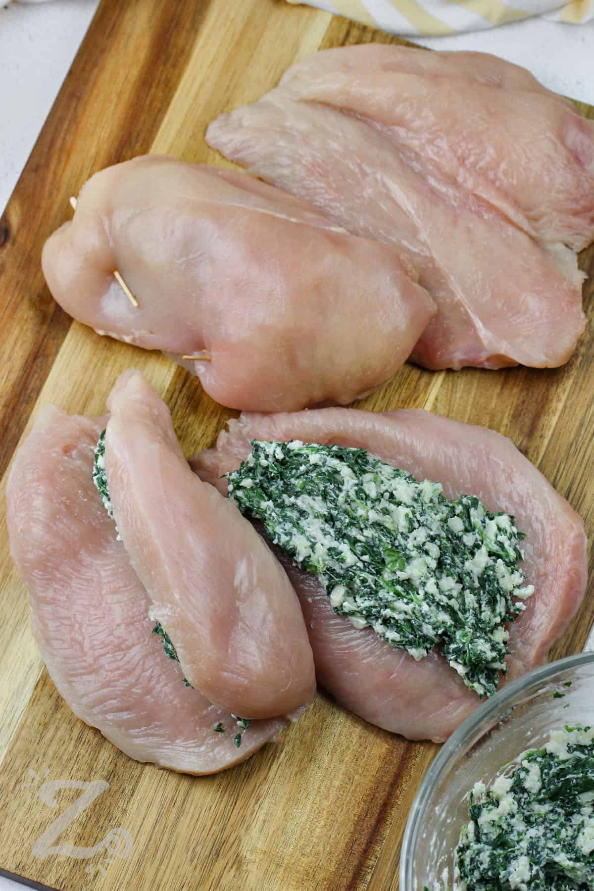cheese filling being put inside chicken breasts to make Spinach Stuffed Chicken Breasts.