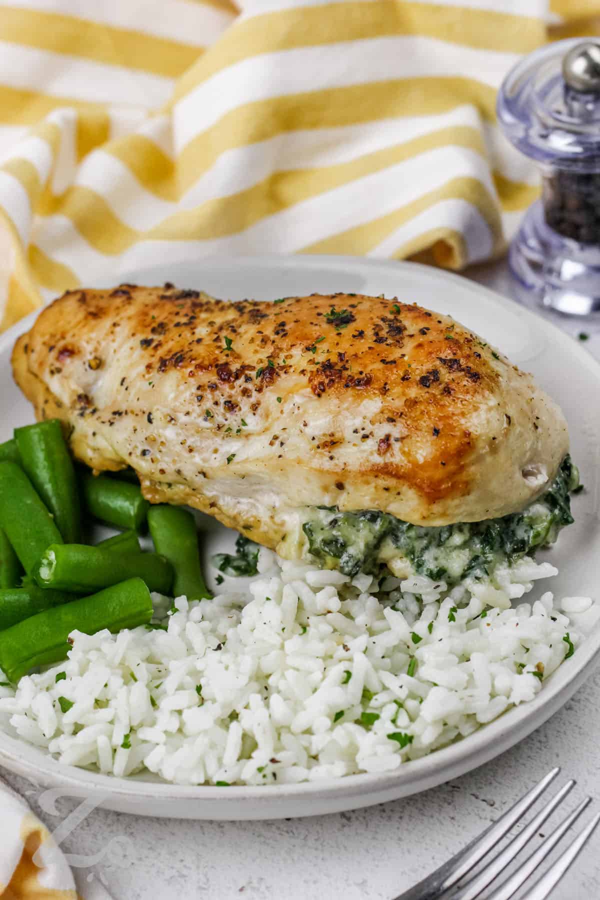 Spinach Stuffed Chicken Breasts on a plate with rice and green beans