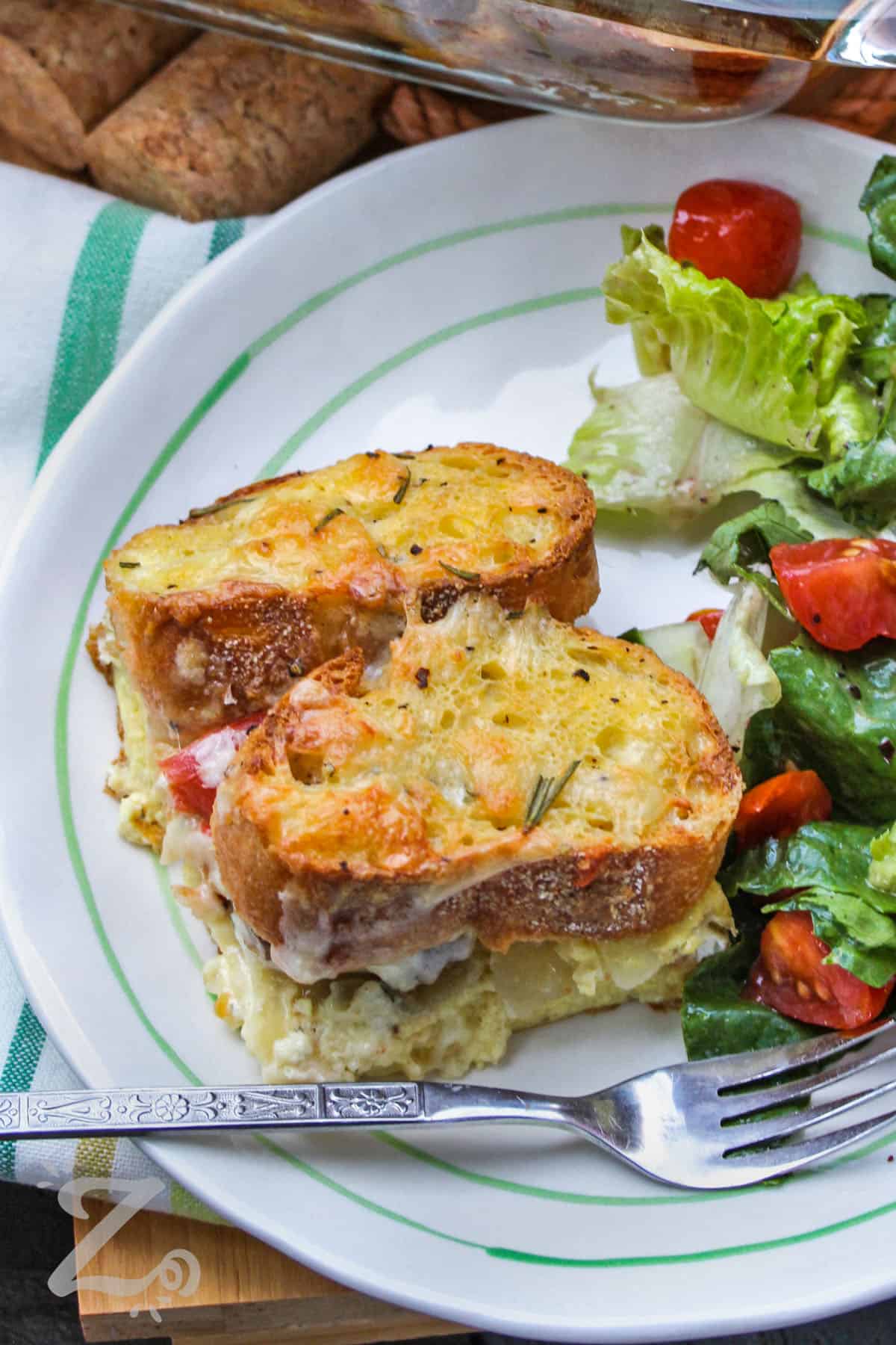 Breakfast strata with sausage on a plate with a tossed salad on the side