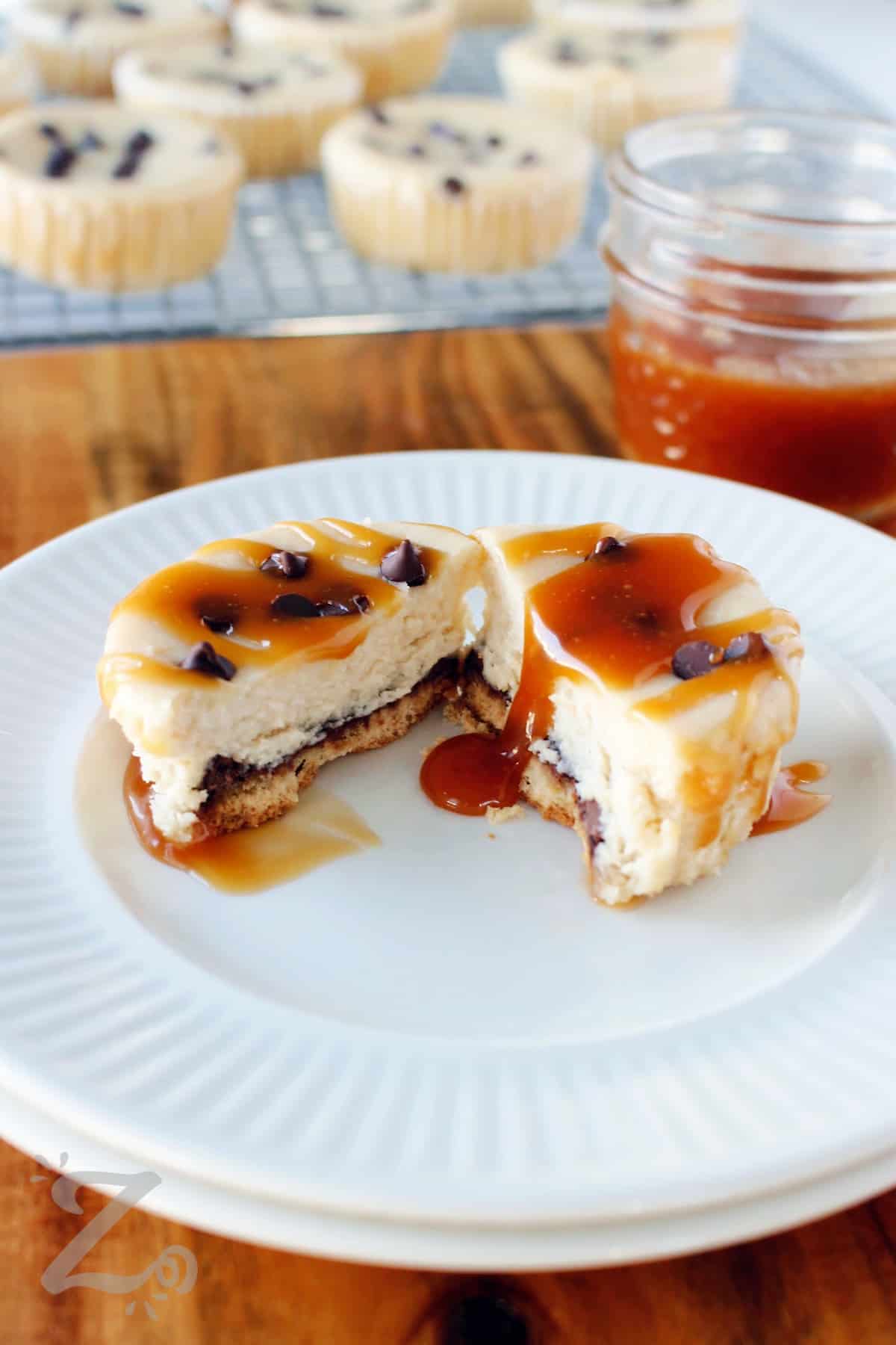 one of the caramel mini cheesecakes sliced in half on a white plate