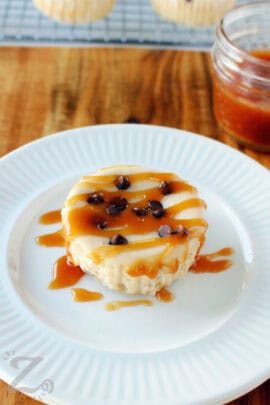 close up of one of the caramel mini cheesecakes with caramel drizzle on a white plate.