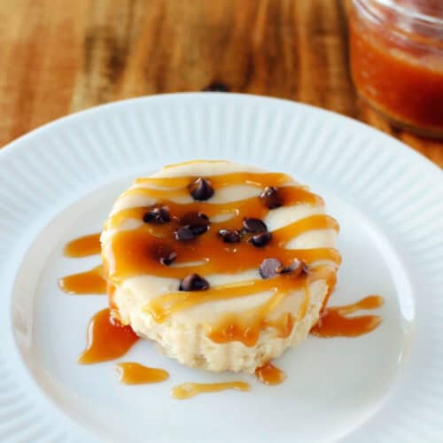 close up of one of the caramel mini cheesecakes with caramel drizzle on a white plate.