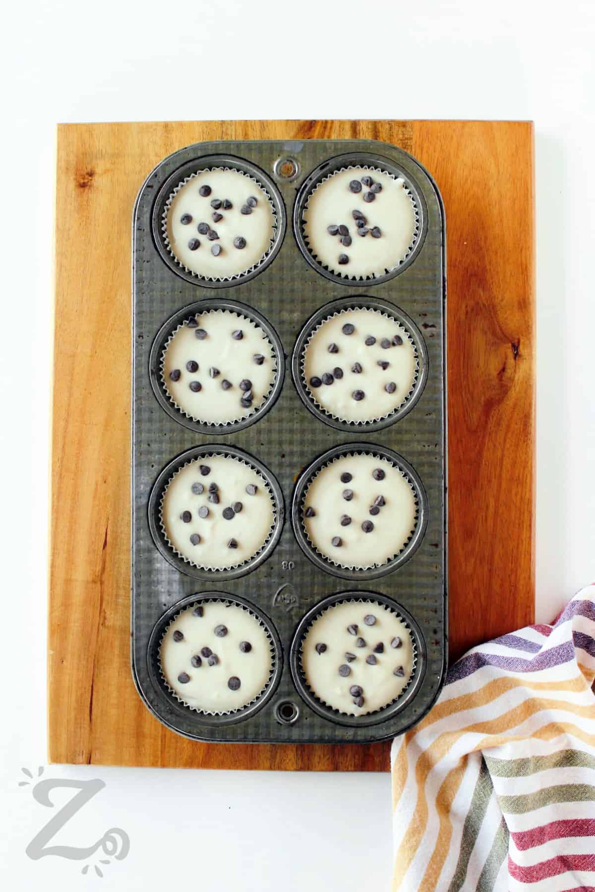 caramel mini cheesecakes in a muffin tin with mini chocolate chips sprinkled on top