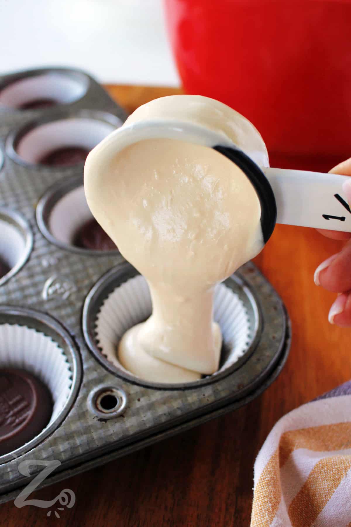 pouring batter on top of a celebration cookie to make caramel mini cheesecakes