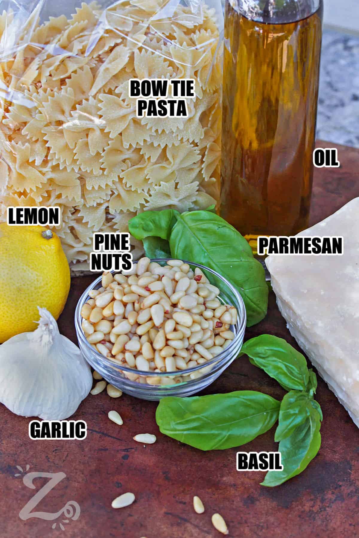 lemon , pine nuts , bow tie pasta , oil , parmesan, garlic and basil with labels to make Bowtie Pesto Pasta Salad