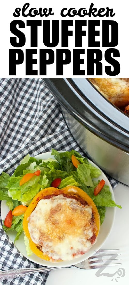 one serving of slow cooker stuffed peppers on a white plate with a side salad beside a Crock pot, with a title