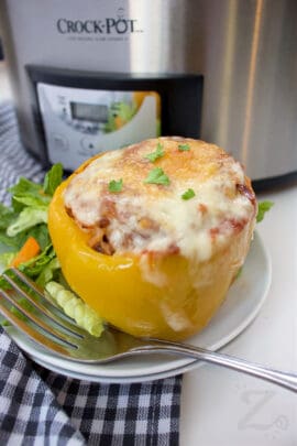 a slow cooker stuffed pepper on a white plate with a garden salad on the side