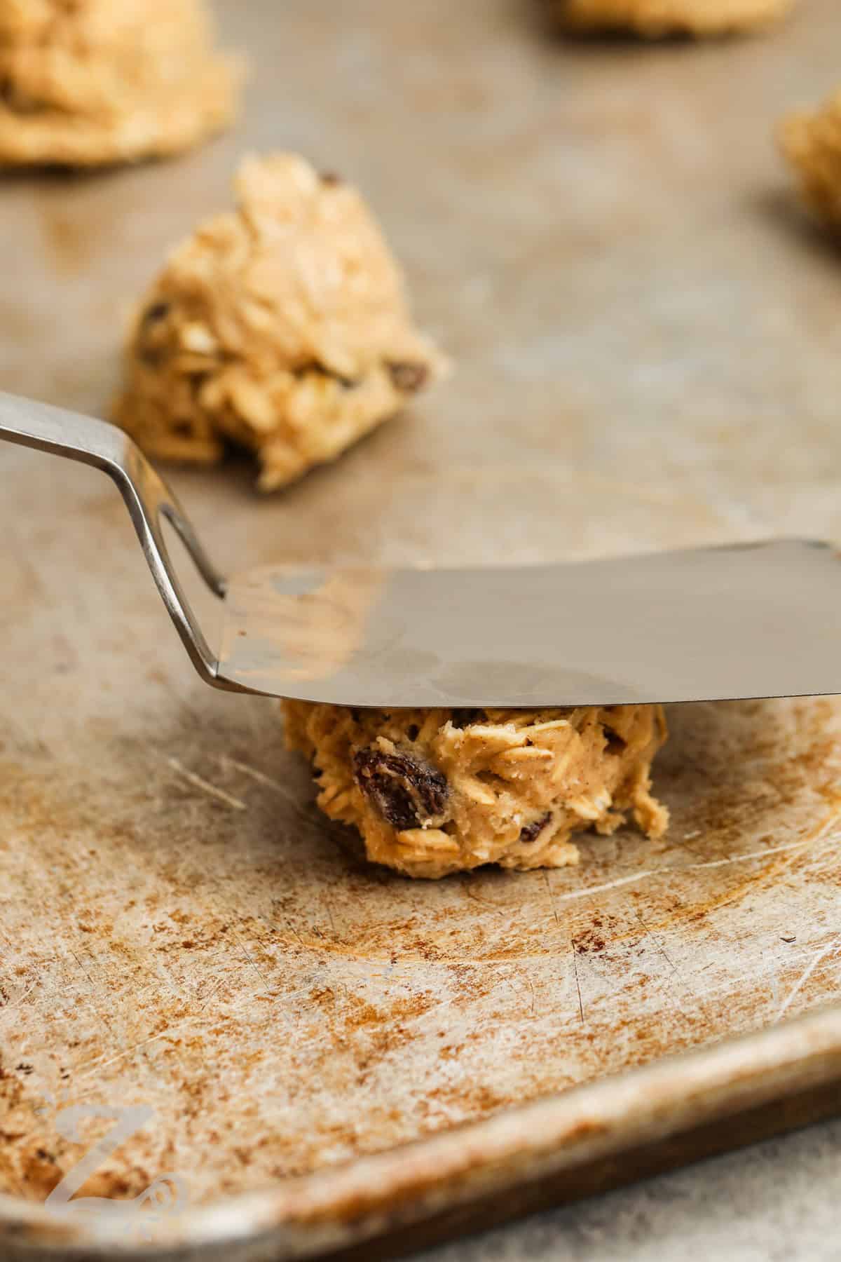 flattening cookies on cookie sheet to make Oatmeal Raisin Cookies