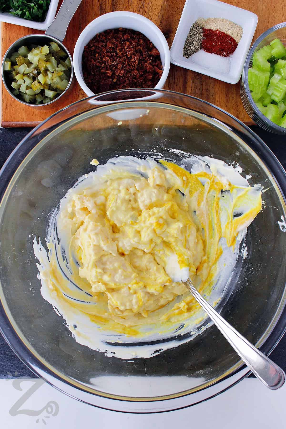 process mixing egg yolks with mustard and mayonnaise to make cauliflower potato salad