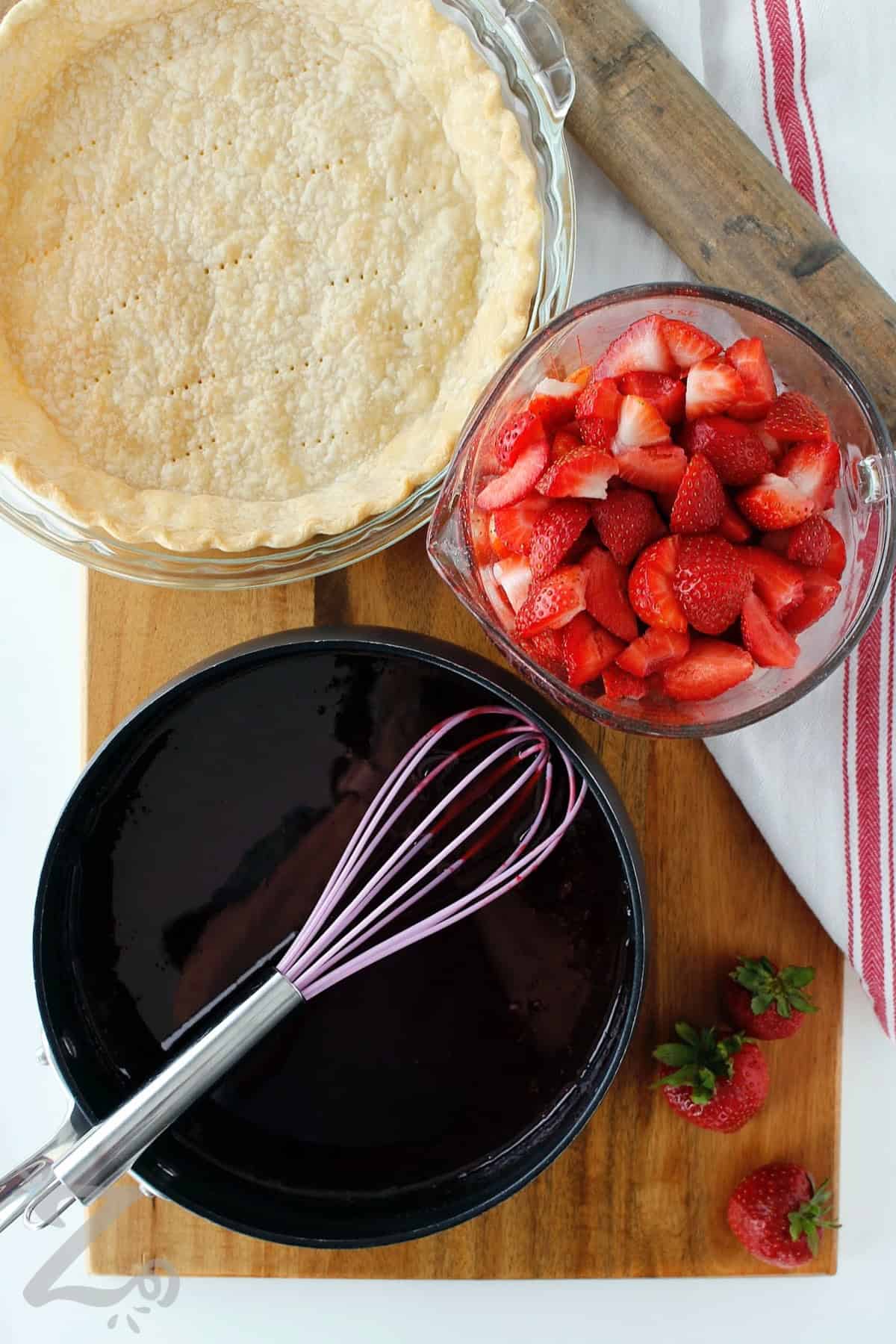 cooked strawberry glaze in a pot with strawberries and baked pie shell on the side, to make Fresh Strawberry Pie