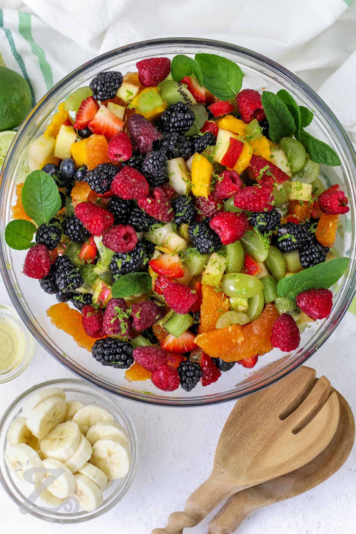 this recipe for fruit salad is easy and colorful mixed in a clear bowl with mint and lime zest garnish