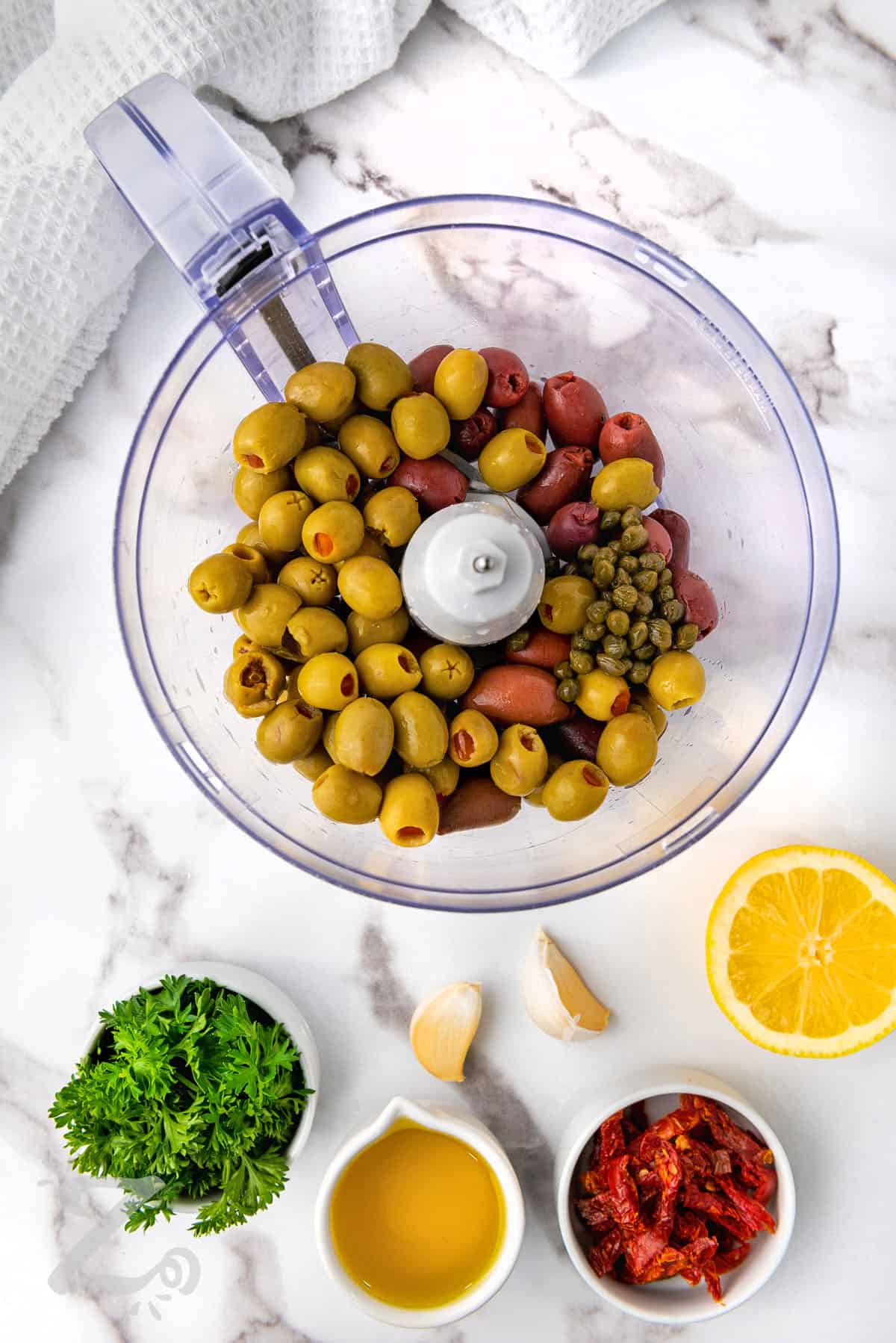 ingredients to make Olive Tapenade in a food processor and in dishes