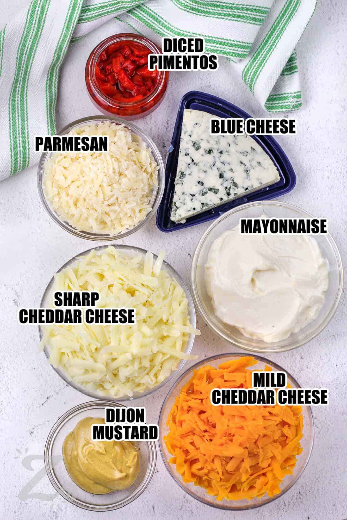 ingredients to make pimento cheese sandwich labeled: diced pimentos, parmesan, blue cheese, sharp and mild cheddar cheese, mayonnaise, and dijon mustard.